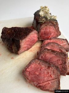 Broiled steak sliced and topped with compound butter