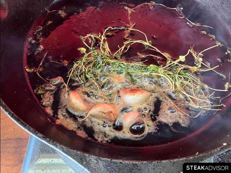 Garlic cloves and butter with fresh herbs in a pan