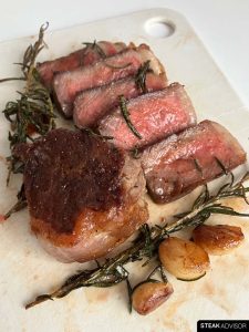 Pan-seared steak sliced and topped with rich garlic butter and fresh herbs