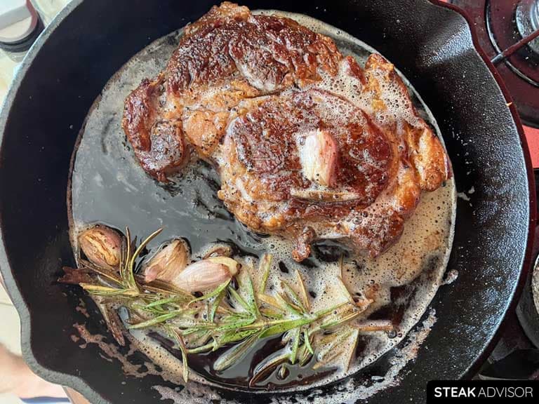 Ribeye steak, seared in a cast-iron skillet with garlic, butter, and rosemary