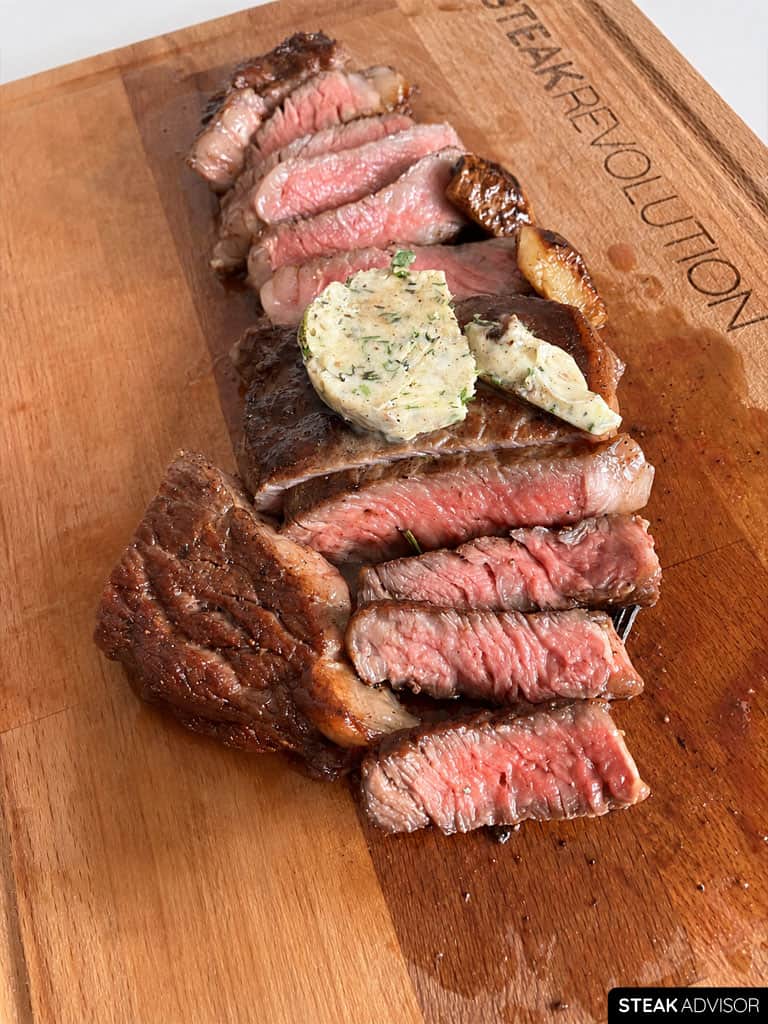 Sliced ribeye steak served with garlic herb compound butter.