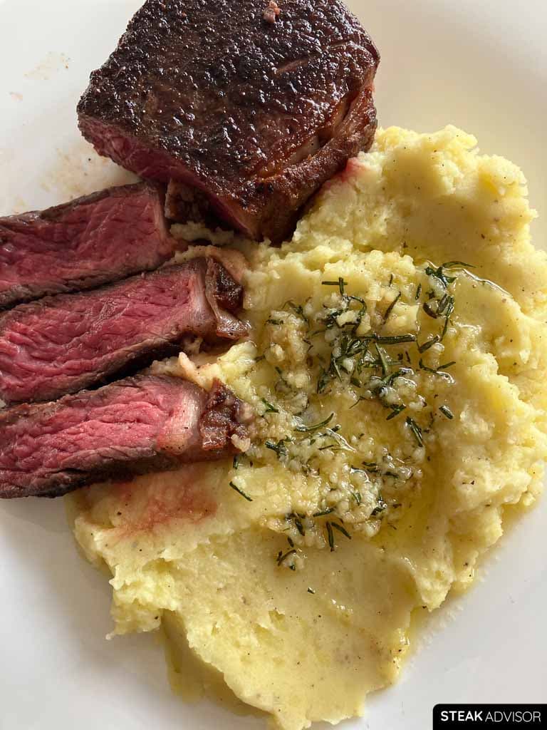 Sliced steak served with garlic herb mashed potatoes vertical photo