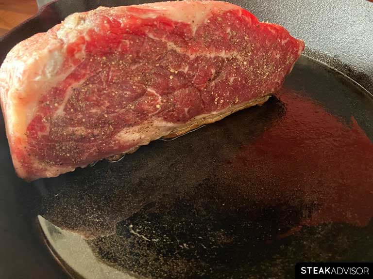 Steak seared fat-side down in a hot pan.