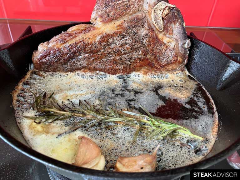 T-bone steak, seared in a cast iron skillet with butter, rosemary, and garlic.