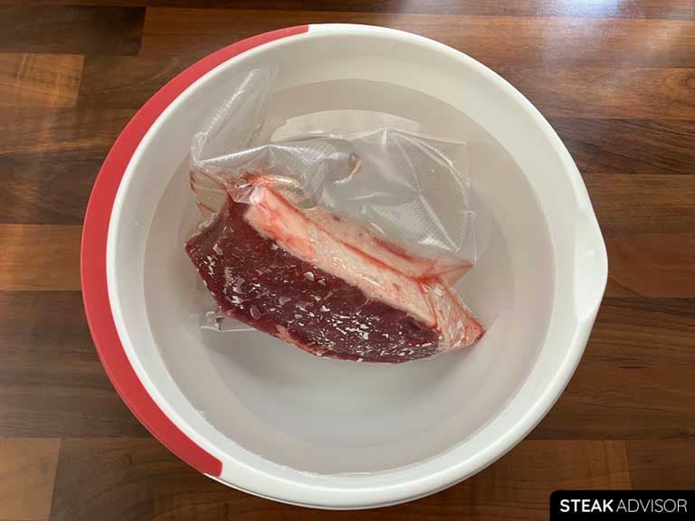Thawing the steak in a bowl of cold water
