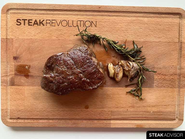 cooked top blade steak with rosemary and garlic on a wooding board 2