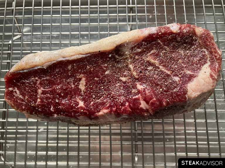 Dry-aged steak seasoned with finely ground black pepper and kosher salt.