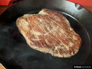 Flank steak cooked in a cast iron skillet on the stovetop