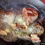 flat iron steak seared in a cast iron skillet with butter, rosemary, and garlic.