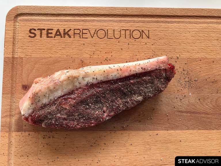 raw picanha steak on a wooden board with the Steak Revolution logo