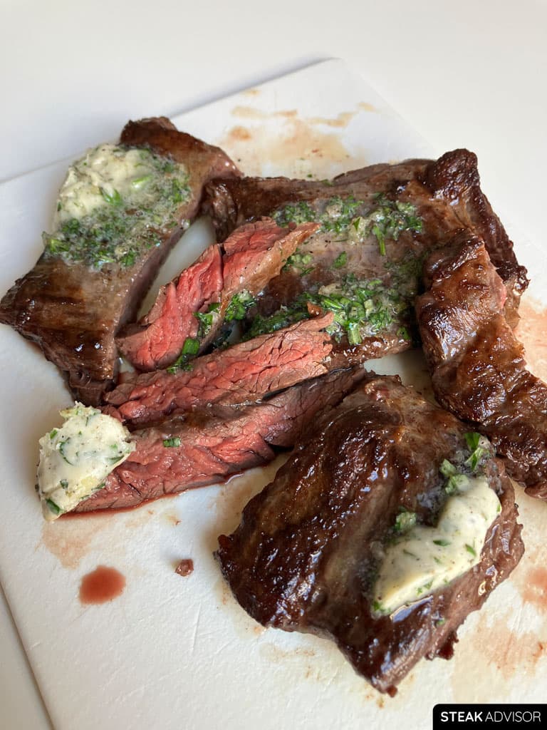 Sliced pan-seared outside skirt steak with compound butter.